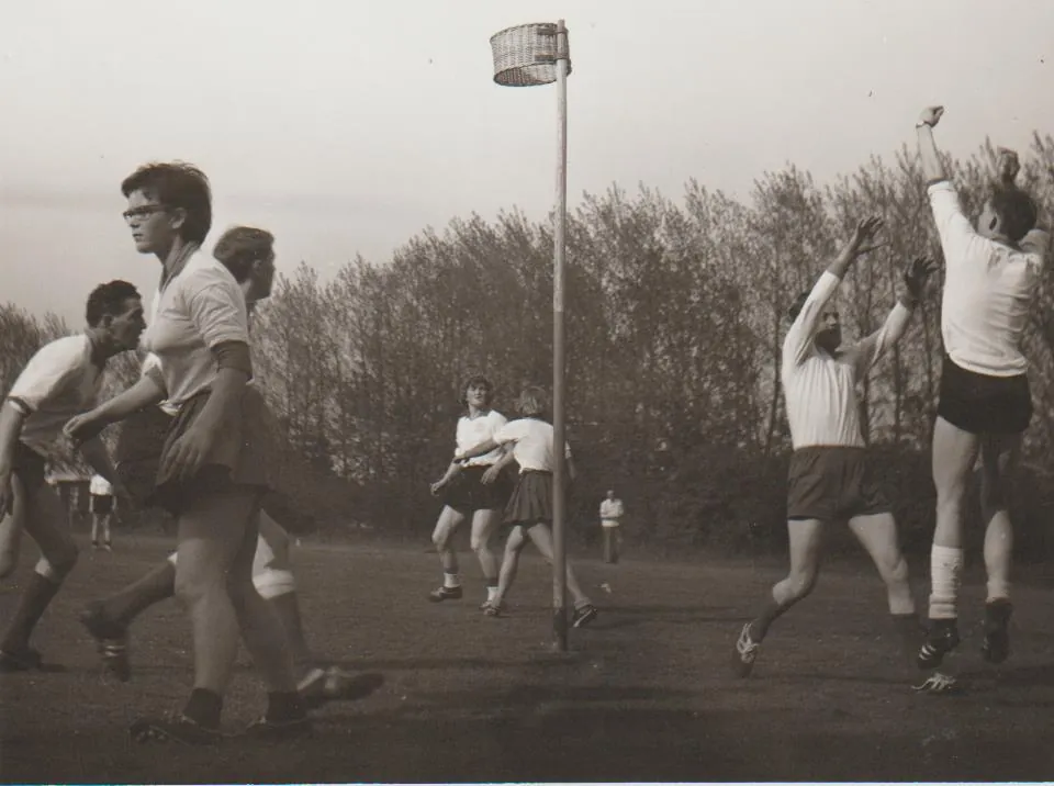 Spelers springen naar de bal tijdens een wedstrijd op het veld, in zwart-wit