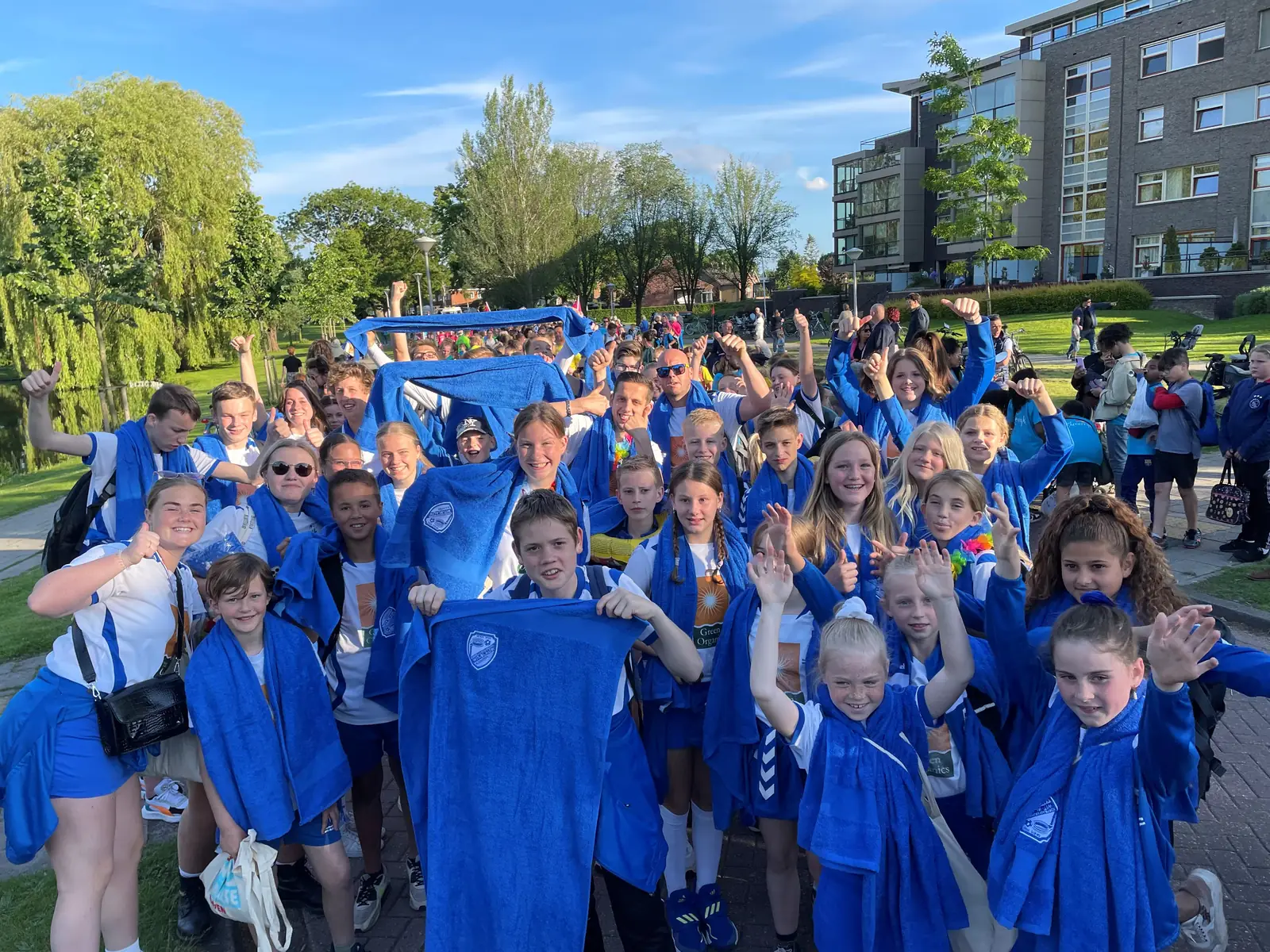 Een grote groep kinderen in blauwe clubkleding juicht tijdens de avondvierdaagse