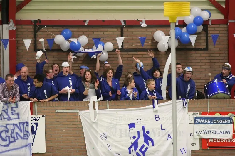 Supporters in het blauw juichen op de tribune, met trommels en ballonnen