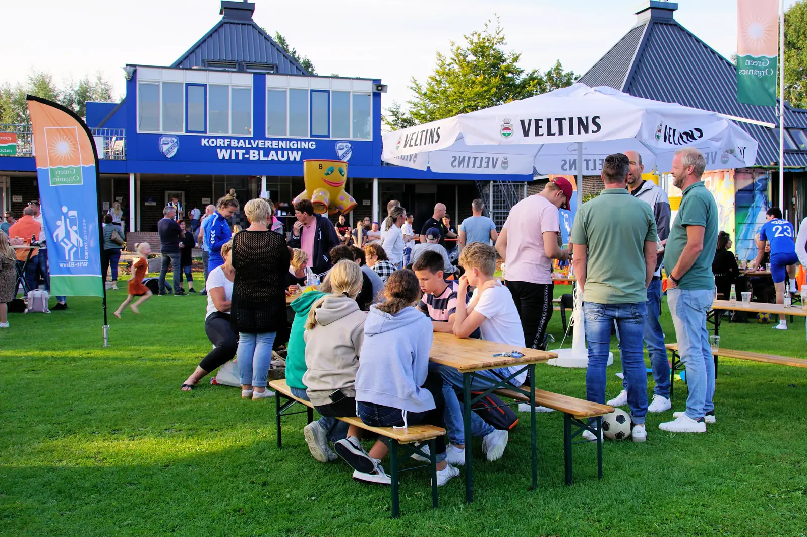 Leden en ouders zitten op het terras bij het clubhuis van Wit-Blauw