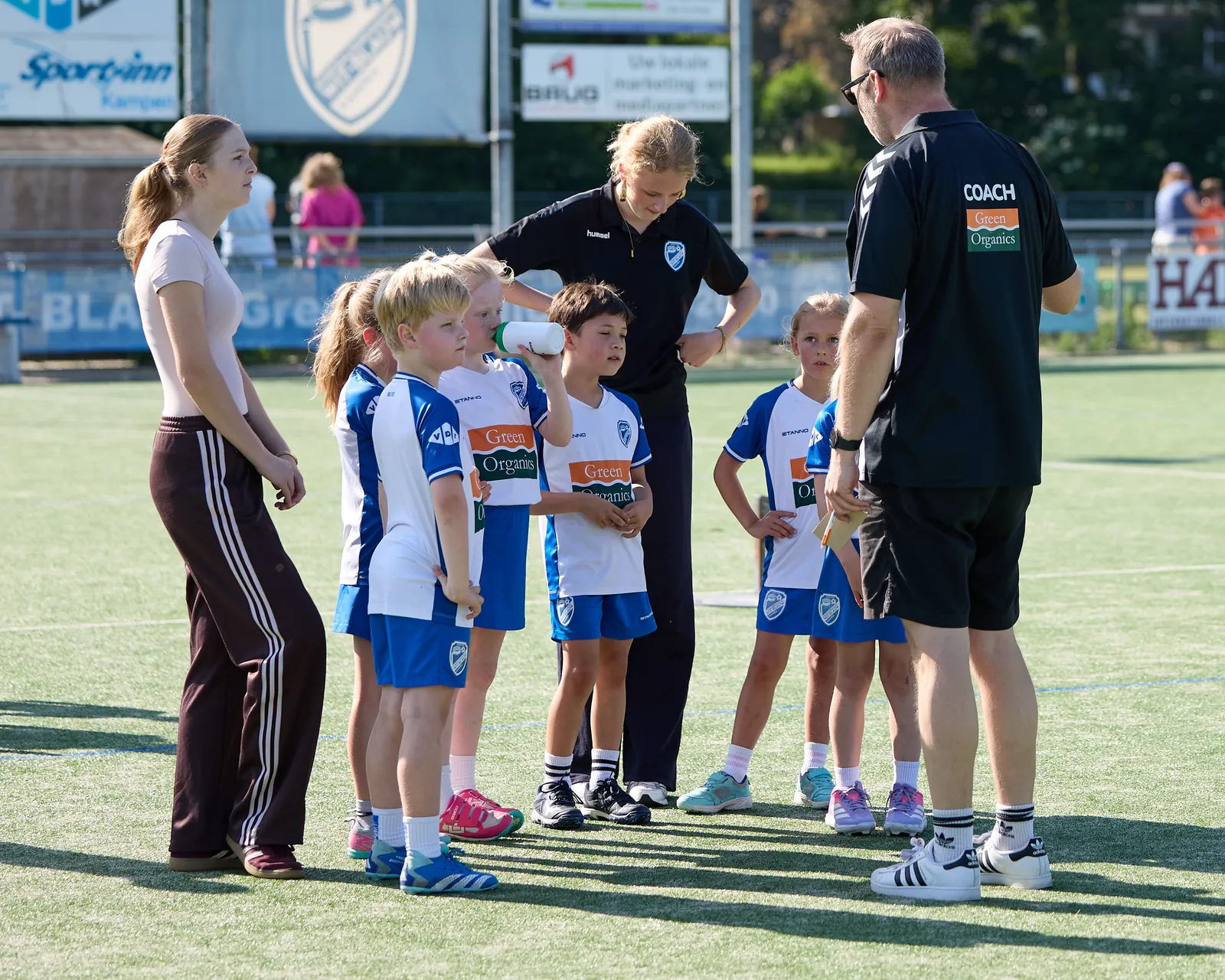 Jeugdspelers luisteren op het veld naar hun coach en trainsters
